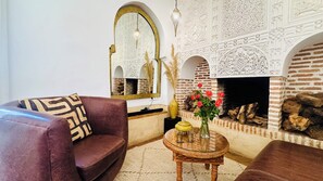A living room with a fireplace, a sofa, a coffee table, and decorative items. - Riad  Dar Eternity (Marrakech)