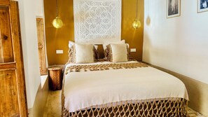 Un dormitorio con una cama, dos lámparas de pared, un panel decorativo y una puerta de madera.