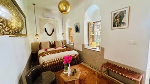 Una habitación con cama, un banco, una mesita y una lámpara colgante.