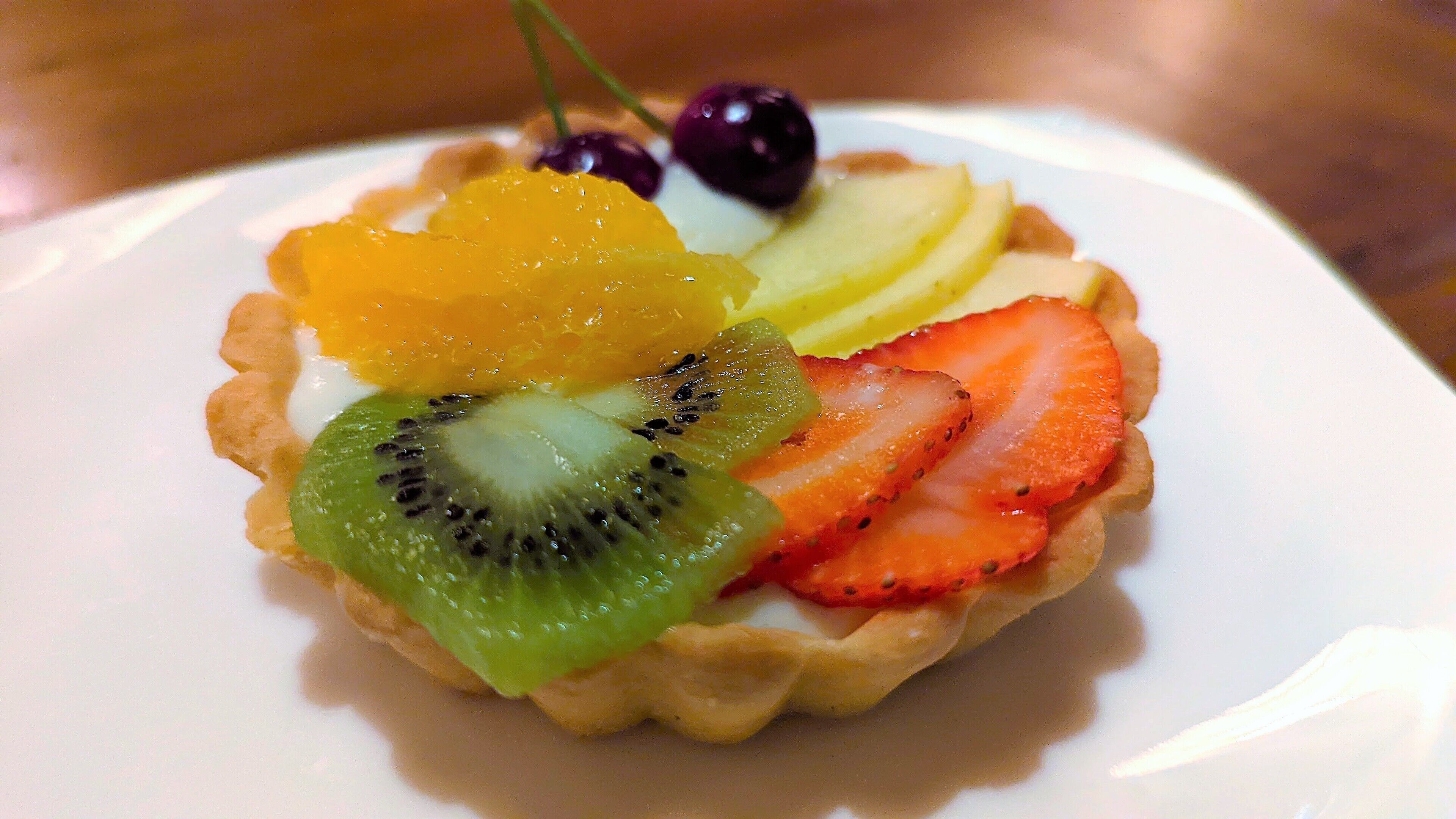 A dessert with a fruit tart on a white plate.