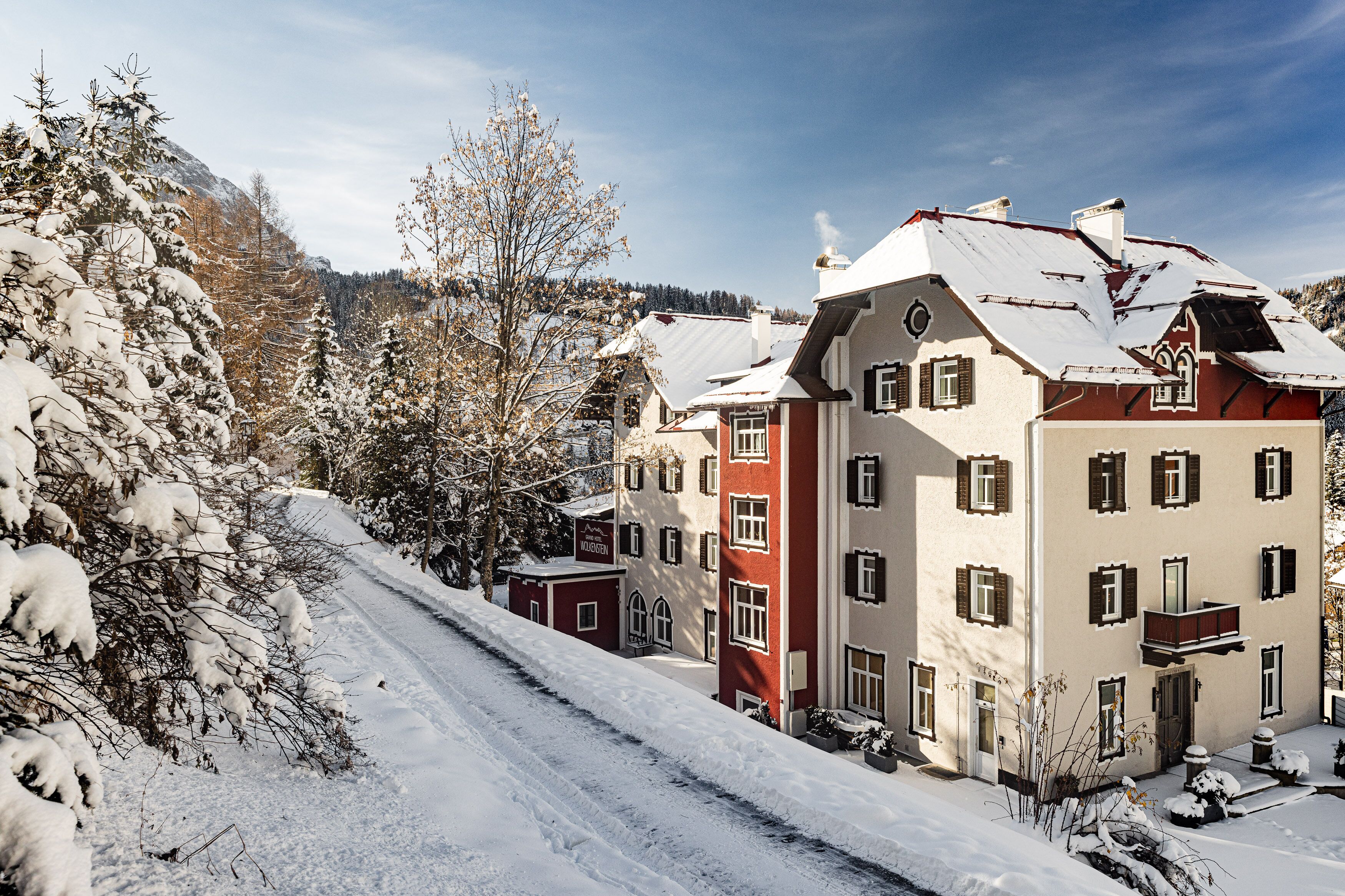 A snow-covered street with buildings, including a red and white structure with multiple windows and a balcony.