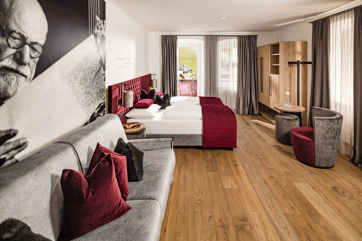 Et moderne hotelværelse med sofa, seng, et lille bord og udsigt til det fri.