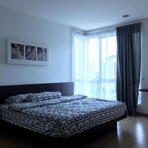 A bedroom with a large bed, a window with curtains, and three framed pictures on the wall.