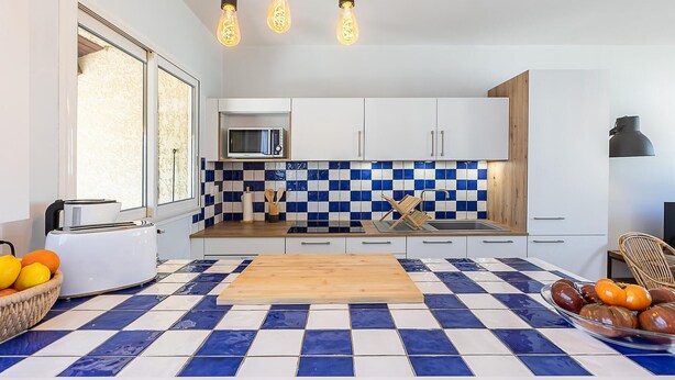 A modern kitchen with a checkered tile floor, a wooden cutting board, a toaster, and a fruit bowl. - 2 bedroom awesome home in Serignan (Serignan)