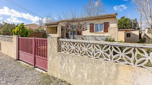 A residential property with a gated entrance, a small house with a tiled roof, and a decorative fence. - 2 bedroom awesome home in Serignan (Serignan)
