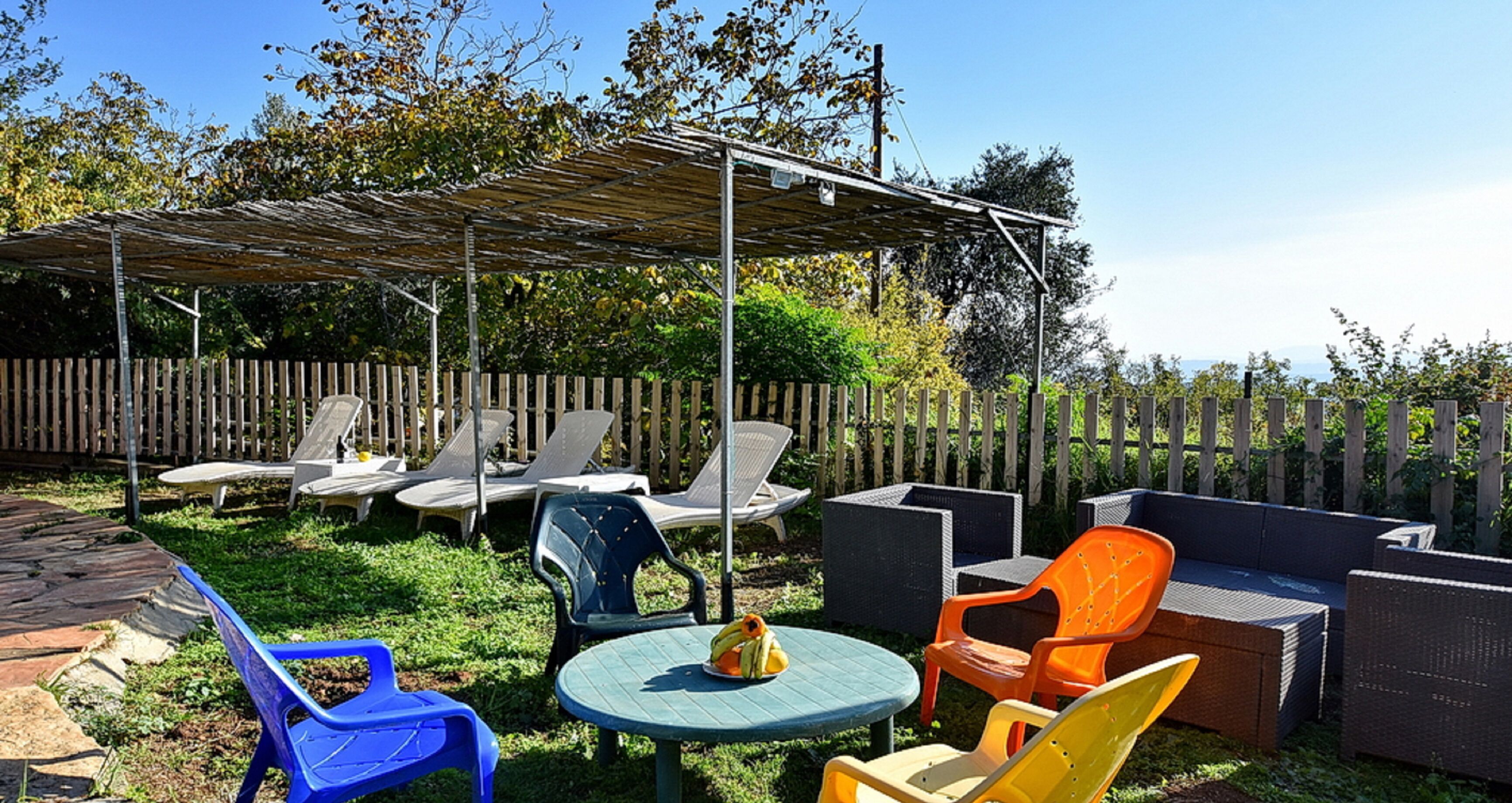 A patio area with outdoor furniture, including chairs and a table, under a pergola.