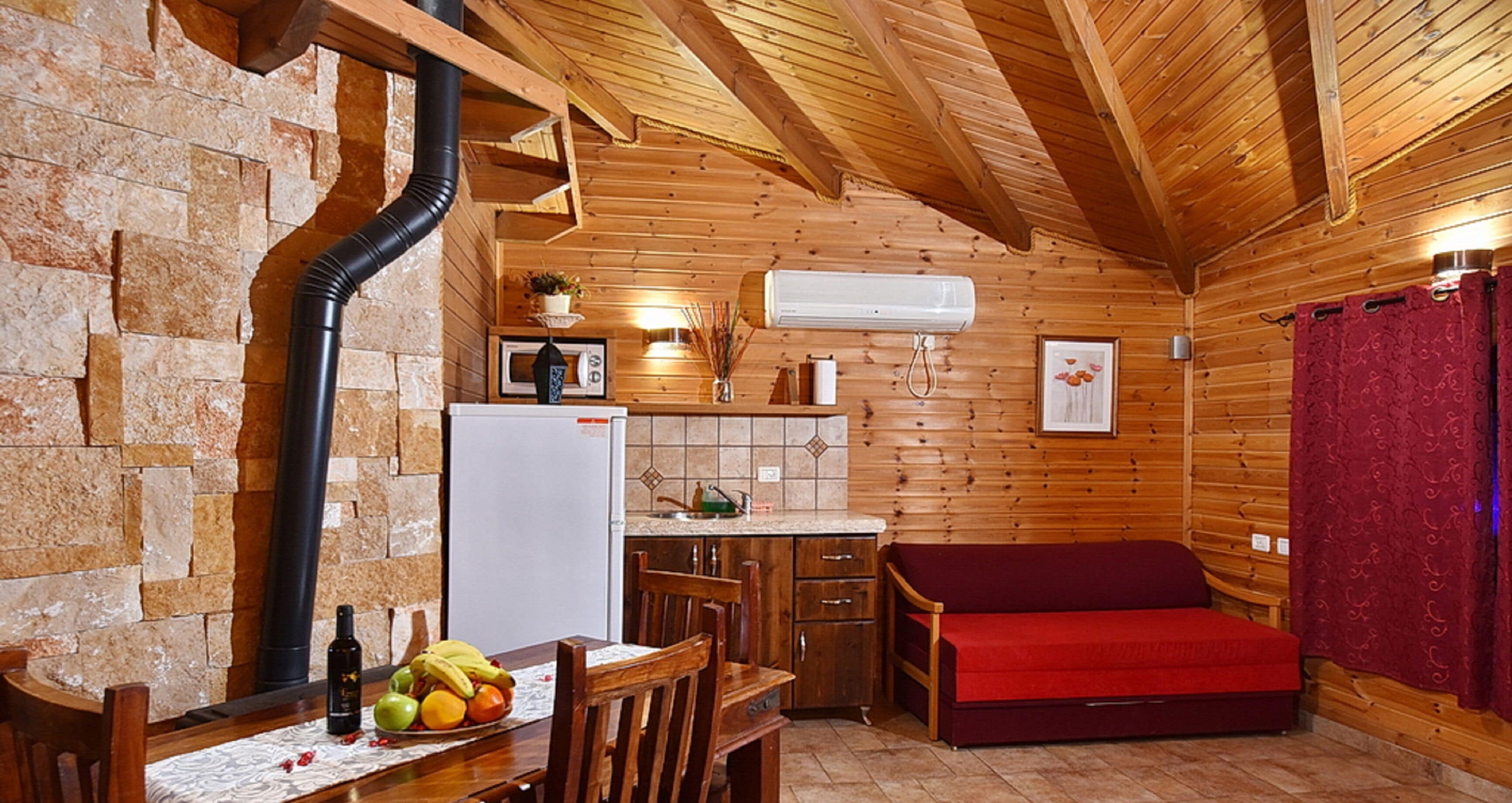 L’intérieur d’un chalet confortable, avec une cuisine, un coin repas et un canapé rouge.