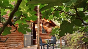 A rustic log cabin with a wooden deck and outdoor seating area. - Niflaot Hagalil (Merom HaGalil)