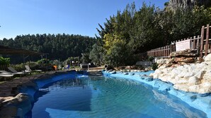 A swimming pool with clear water, surrounded by rocks and a wooden fence. - Niflaot Hagalil (Merom HaGalil)