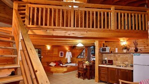 A wooden cabin interior with a loft bedroom, a kitchen, and a dining area. - Niflaot Hagalil (Merom HaGalil)