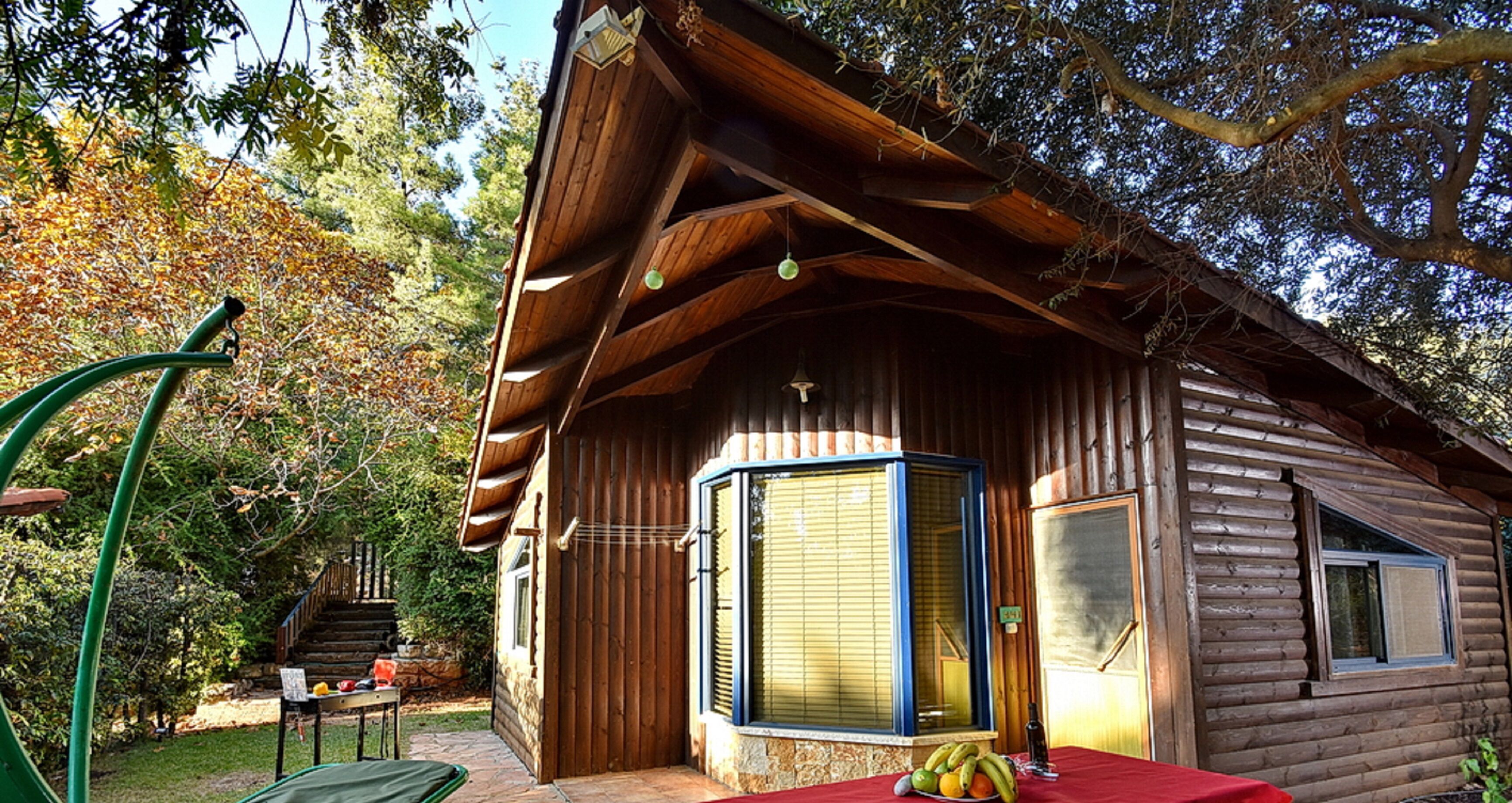 A log cabin with a wooden exterior, a covered porch, and a table with fruits and a bottle.