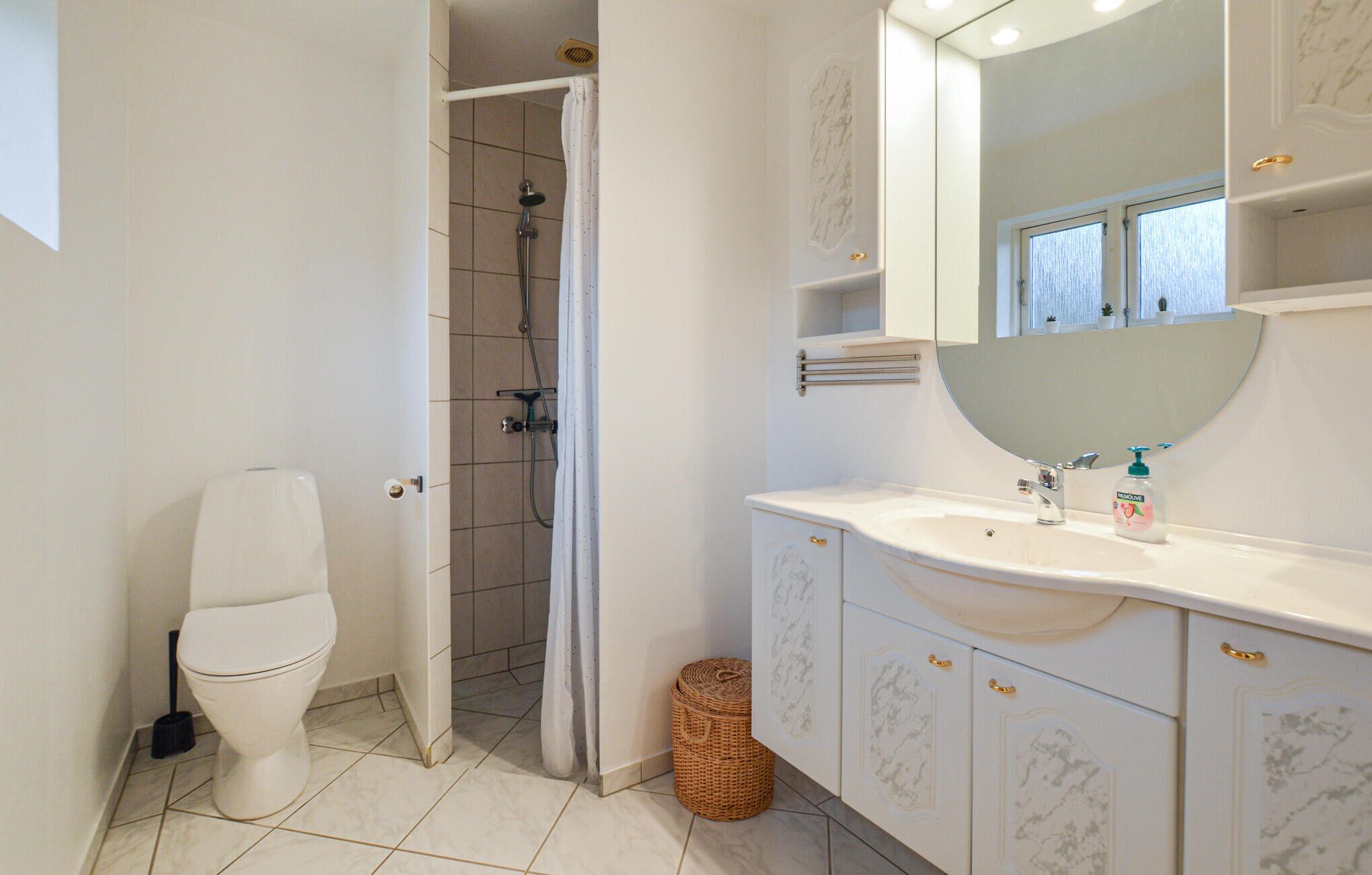 Un bagno con toilette, doccia e lavabo con specchio.