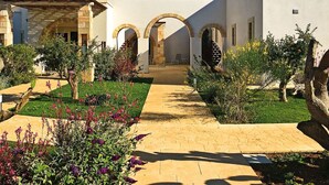 A courtyard with a paved walkway, arches, and various plants. - Beautiful apartment for 6 guests with A/C, pool, WIFI, TV and panoramic view (Otranto)