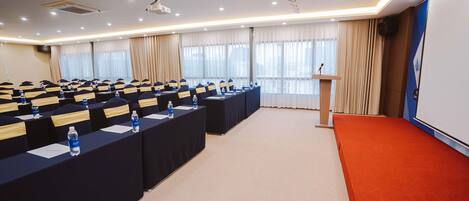 A conference room with rows of tables, each with name cards and water bottles.