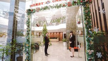 A hotel entrance decorated for Christmas with a 'Merry Christmas' sign, a Christmas tree, and festive garlands.