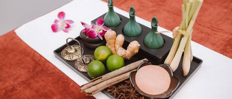 A tray with various items including a flower, ginger, cinnamon sticks, star anise, and a bowl of pink substance.