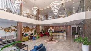 Um hall amplo com teto alto, luminárias modernas e um balcão de recepção.