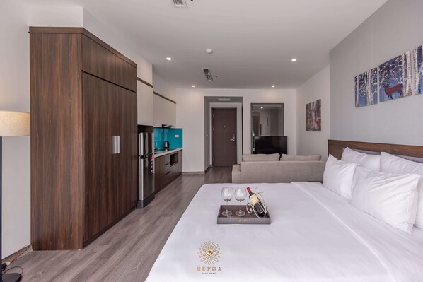 Habitación de hotel con una cama grande, un minibar, un televisor y un cuadro en la pared.