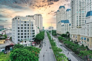 A multi-story hotel with a modern design, located along a busy urban street with trees and vehicles. - Reyna Hotel Hanoi (Hanoi)