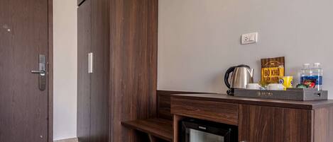 A modern kitchen with wooden cabinetry, a built-in refrigerator, and a countertop with a kettle and coffee maker.