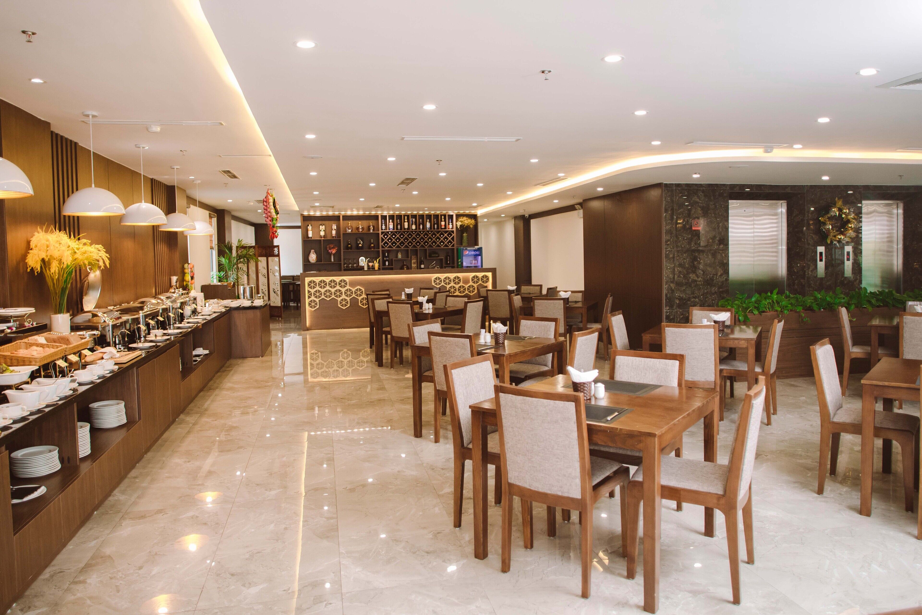 A modern hotel dining area with a buffet, wooden tables, and chairs.