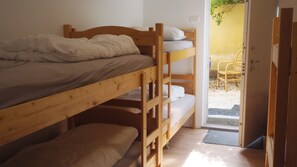 A bunk bed room with a door leading to an outdoor area with a chair and a small table.