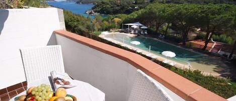 A balcony with a view of a pool and mountains.