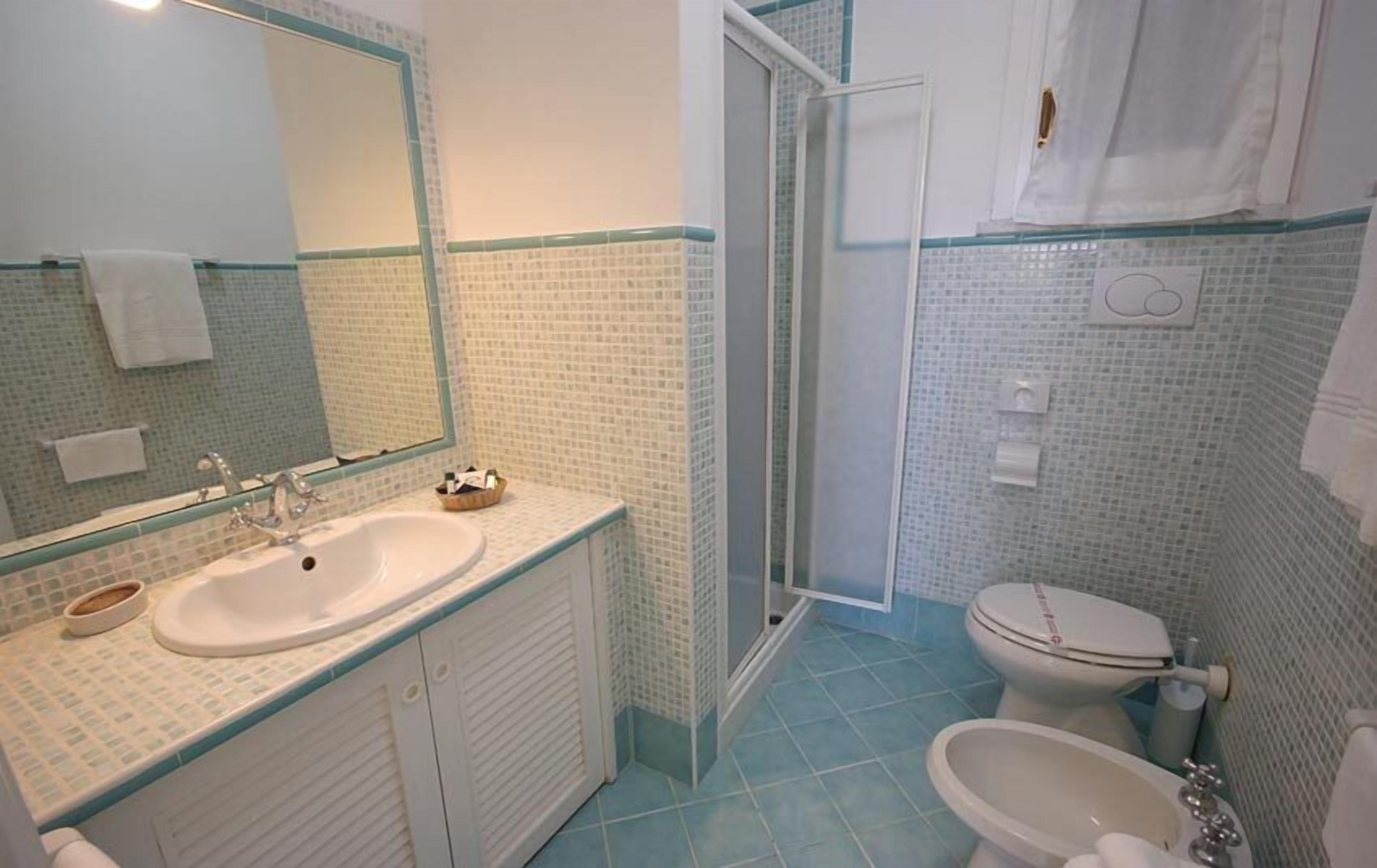 Un bagno con lavandino, specchio e water.