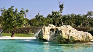 A clear pool with a rock formation in the center, surrounded by trees and a stone wall. - Beautiful apartment for 6 people with A/C, WIFI, pool, TV and panoramic view (Otranto)