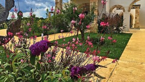 A garden with pink flowers and a stone structure. - Beautiful apartment for 6 people with A/C, WIFI, pool, TV and panoramic view (Otranto)
