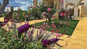 A garden with pink flowers and a stone structure.