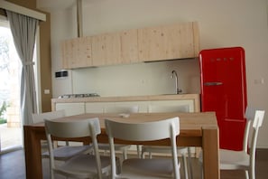 A compact kitchen with wooden cabinets, a red refrigerator, and a dining table with chairs.