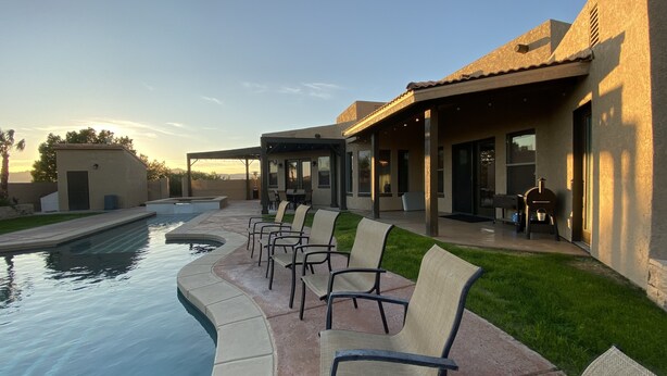 A poolside area with chairs and a covered patio. - Guitar Shaped Pool ! (Bullhead City)