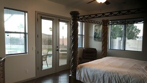 A bedroom with a four-poster bed, a ceiling fan, and a view of the outside through large windows. - Guitar Shaped Pool ! (Bullhead City)