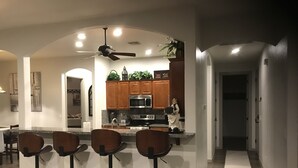 A modern kitchen with a central island, bar stools, and a ceiling fan. - Guitar Shaped Pool ! (Bullhead City)