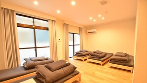 Una habitación con suelo de madera, una mesa de masaje y varias camillas con toallas.