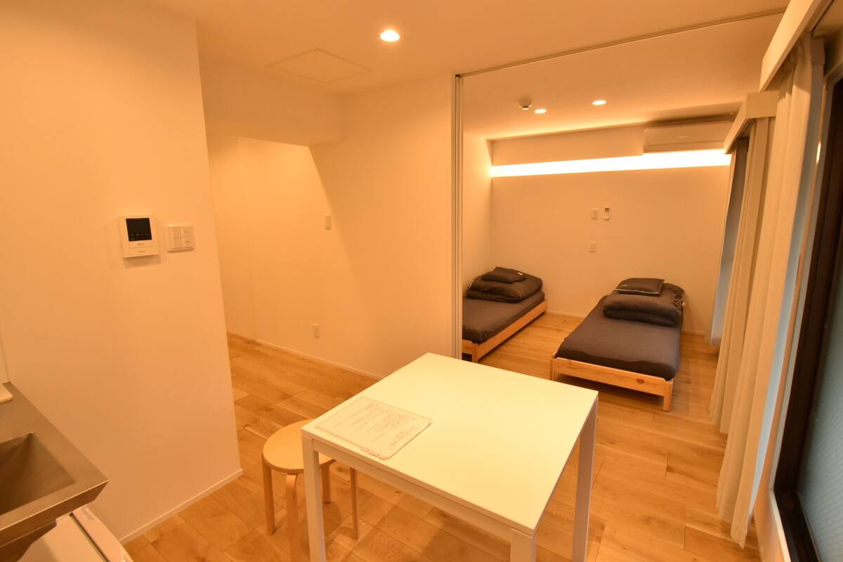 A compact hotel room with a single bed, a small table, and a mirror.