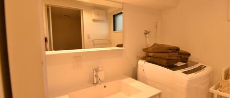 A bathroom with a sink, mirror, and stacked towels.