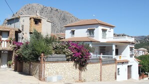 Une maison à deux étages avec une façade en pierre, un toit en tuiles et un balcon.