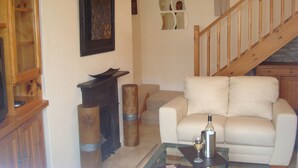 A living room with a white sofa, a glass coffee table, a fireplace, and a wooden staircase. - Carrig Beag (Kenmare)