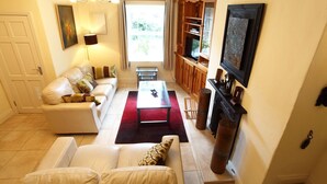 A living room with a sofa, a coffee table, a fireplace, and a television. - Carrig Beag (Kenmare)