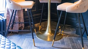 Eine Sitzecke mit zwei Sesseln und einem Tisch, ein Spiegel an der Wand und gemusterte Vorhänge.
