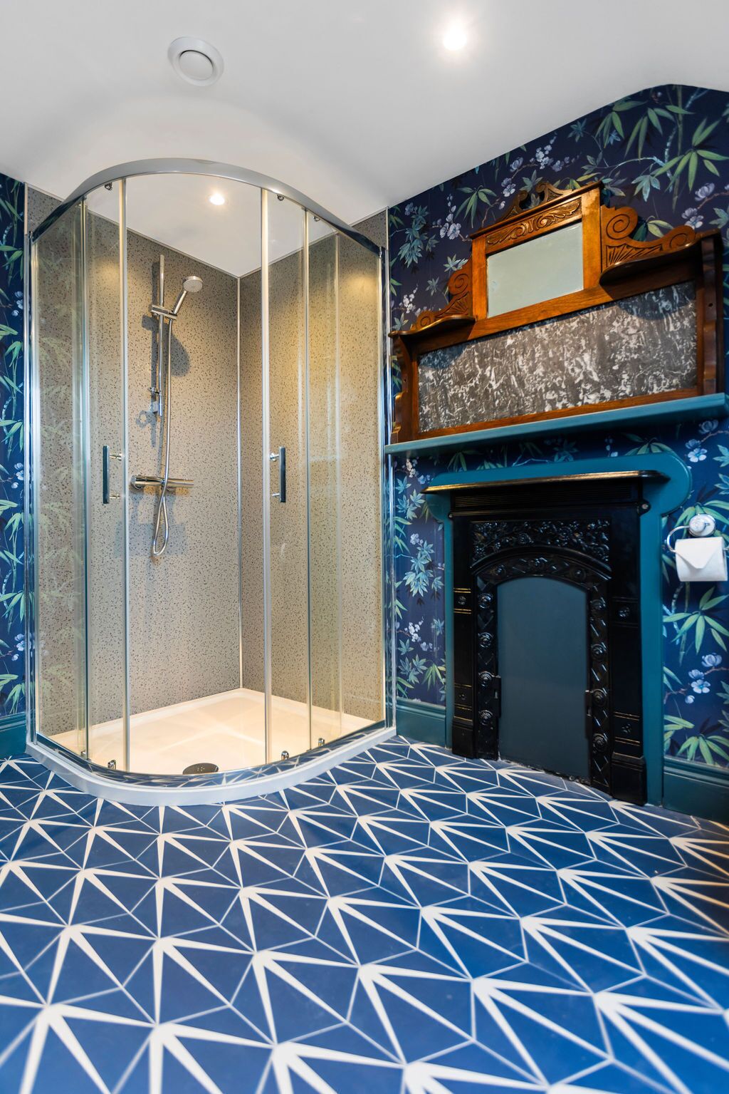 Une salle de bain dotée d’une douche à parois de verre, d’un sol carrelé et d’une cheminée décorative.