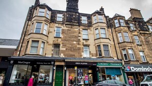 A multi-story building with various storefronts including a hairdressing salon, a pharmacy, and a Domino's pizza shop. - Beautiful and Bright Georgian Style Morningside Apartment - Pass the Keys (Edinburgh)