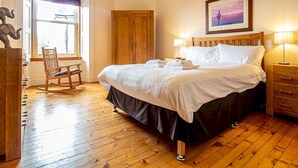 A bedroom with a large bed, wooden flooring, a wooden wardrobe, a rocking chair, and a window with a view. - Beautiful and Bright Georgian Style Morningside Apartment - Pass the Keys (Edinburgh)