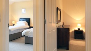 A hotel room with a bed, bedside tables, a dresser, and a mirror. - Ardmullen 4 bed Walnut (Kenmare)