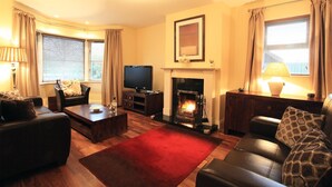 A living room with a fireplace, a television, and a sofa. - Ardmullen 4 bed Walnut (Kenmare)