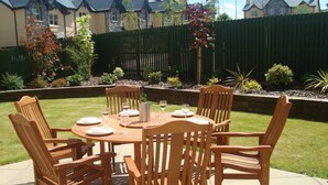 A wooden outdoor dining set with a table and chairs, surrounded by a well-maintained lawn and a wooden fence. - Ardmullen 4 bed Walnut (Kenmare)