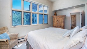 Een slaapkamer met een groot bed, een rieten stoel en een houten kast.