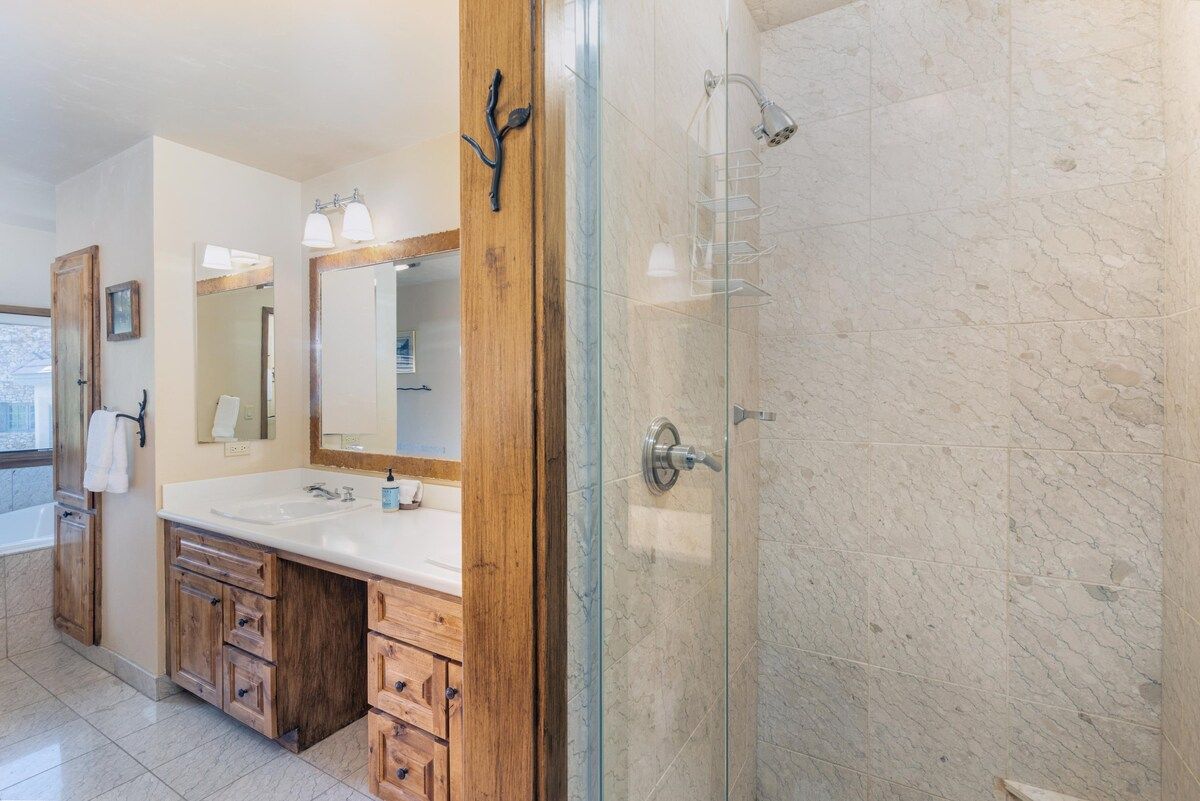 Une salle de bain avec une douche à parois de verre, des meubles en bois et un grand miroir.